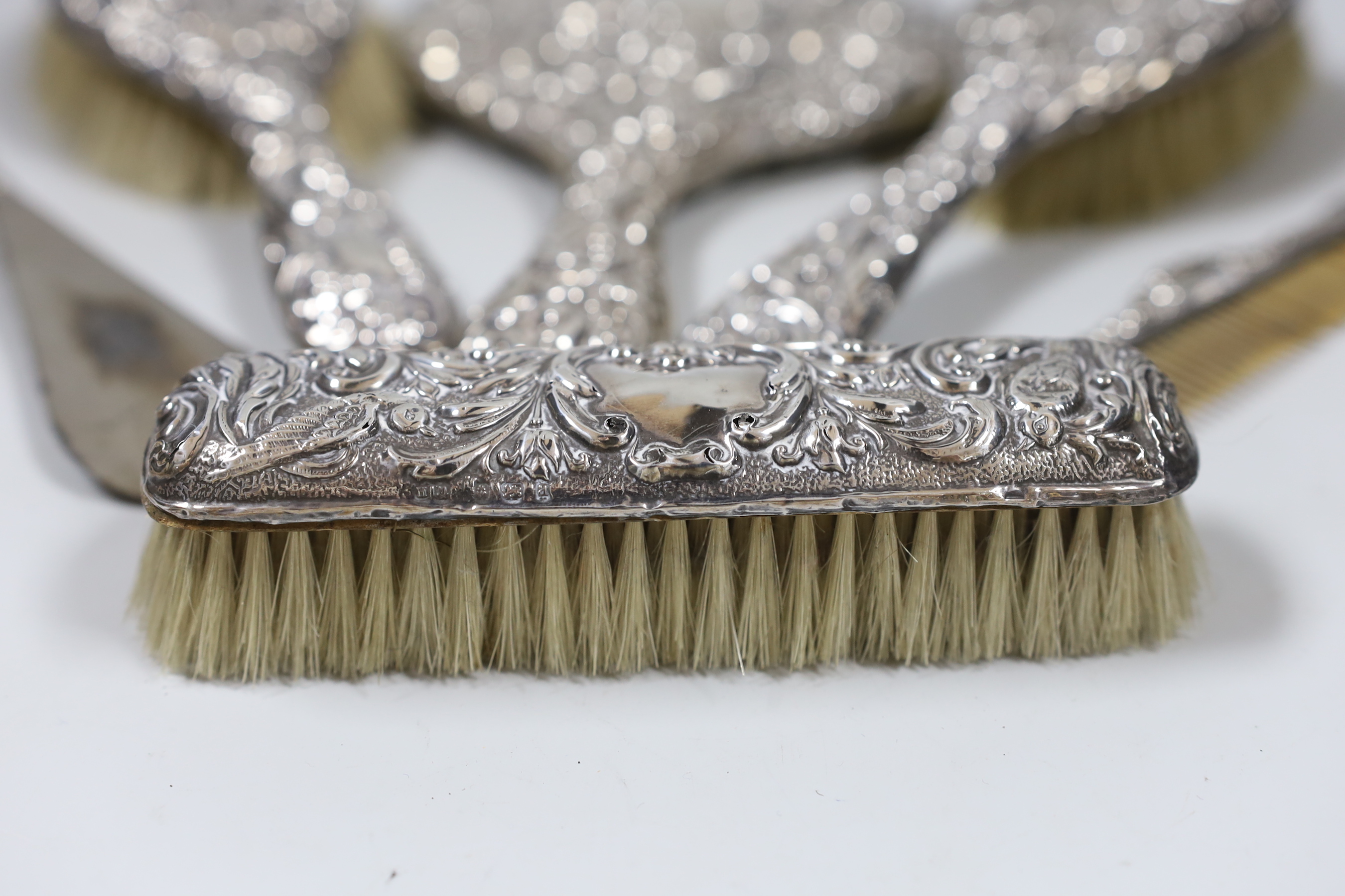 A late Victorian repousse silver mounted six piece mirror and brush set, Chester, 1900.